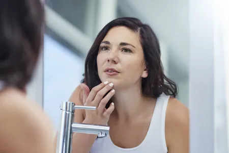 Woman checking her skin in the mirror