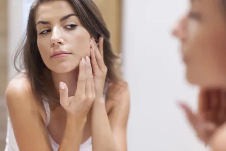 Woman checking her skin in a mirror